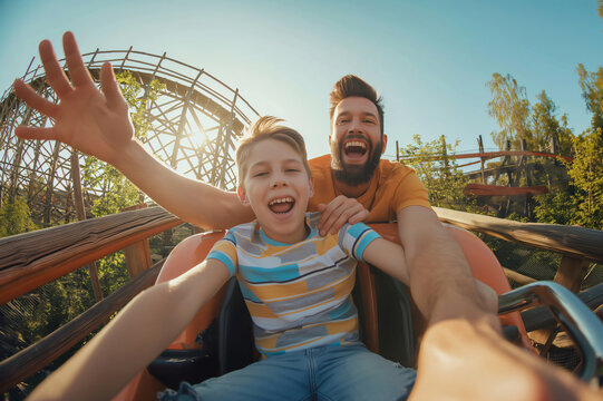 Father and his son are screaming with joy while taking a selfie on a rollercoaster ride
