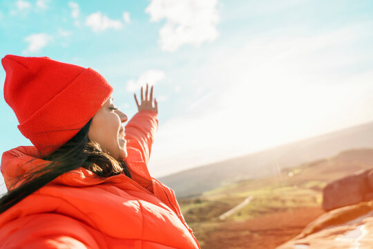 Woman in Red Jacket and Hat Raises Arms in Joy While Hiking on Sunny Day - Powered by Adobe