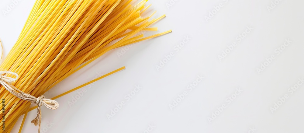 Poster closeup of a bundle of italian long yellow spaghetti against a white backdrop with copy space image.