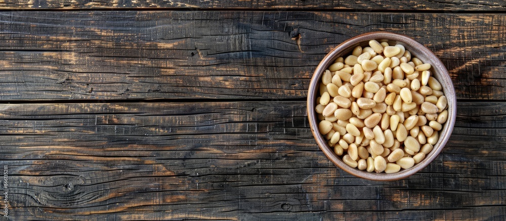 Poster Top view of a bowl with pine nuts on a wooden background, providing space for a text overlay or other elements in the image. copy space available