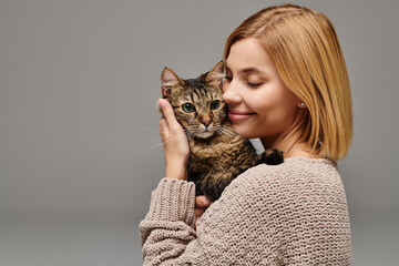 A short-haired woman gently cradling a cat in her hands, showing love and care in a cozy home...