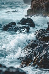 Waves crashing against rocks, with a softly blurred background of a rugged coastline and sea. 