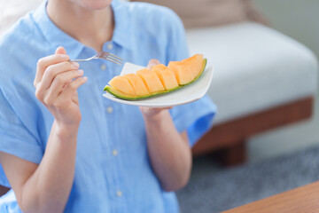 デザートのメロンを食べる女性