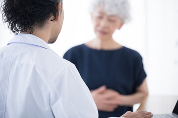Elderly patient complaining to doctor of physical problems, stomach or abdominal pain, etc....
