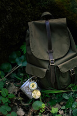 old Traveler's backpack with metal mug and vintage compass in forest, nature background. Hiking...