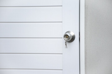 Obraz premium Close up modern white wooden door with silver knob and keys against gray concrete background for forgot to close the door or lost the key and safety with security concept.