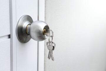 Close up silver knob and keys on white wooden door for the concept of forgetting to lock the door...
