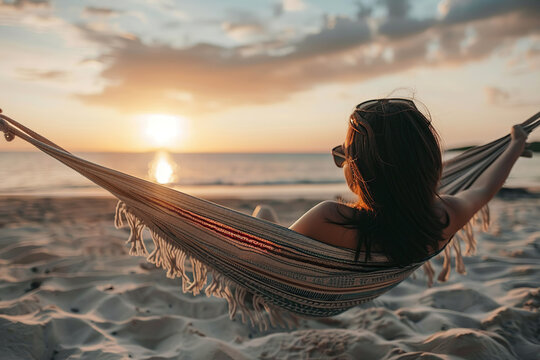 Young woman relaxing on hammock looking at the sunset. 15 August unnual Relaxation Day - Powered by Adobe