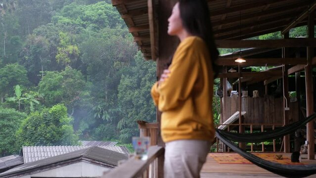 Blurred of a woman standing inside the wooden house and checking with one hand if it's rain