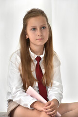 Portrait of a beautiful schoolgirl in a white shirt and a burgundy tie