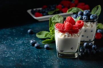 Cottage cheese with cream, raspberries, and blueberries garnished with fresh mint.