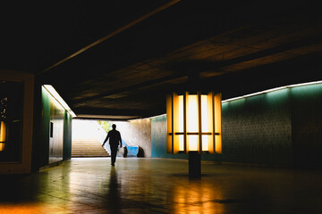 A persons silhouette is cast in an urban underpass, illuminated by ambient city lights, Munich,...