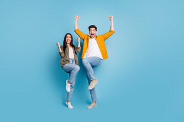 Full body portrait of two young people rejoice raise fists wear shirt isolated on blue color...