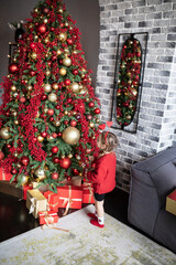 Lovely little girl playing on the floor close to the decorative and festive Christmas tree at wonderful holiday time