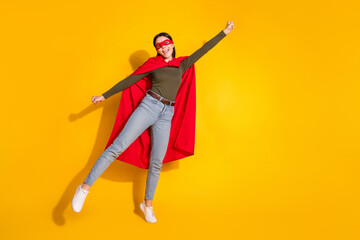 Full length photo of lovely teen lady flying superman costume dressed stylish khaki garment isolated on yellow color background