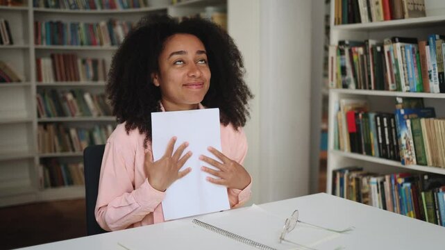 Portrait of happy student got an excellent grade mark for the test at university class cute smiling curly girl looking at test in good mood indoors Exam passed Successful education concept