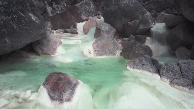 Brook flow with hot sulfur-containing water in the Sorikmarapi volcano area, North Sumatra, Indonesia.