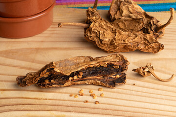 Whole and halved Mexican Chile Chipotle Meco and seed on wooden background close up