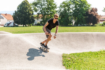 Young handsome man riding a skateboard at the skate park. Fun outdoor action sports activities © Glyph_stock