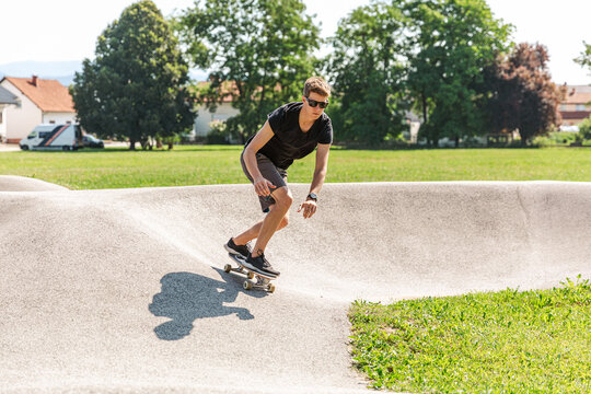 Young handsome man riding a skateboard at the skate park. Fun outdoor action sports activities