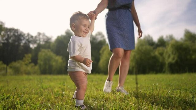 Mom and baby taking the first steps. Child walk step family concept. Mom and baby on steps in the park. Mom and baby lifestyle taking first steps in the. park. family motherhood concept.