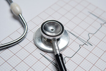 Closeup image of a stethoscope on a electrocardiogram (ECG) printout. The ECG graph shows a normal sinus rhythm. Healthy heart, wellbeing concept.