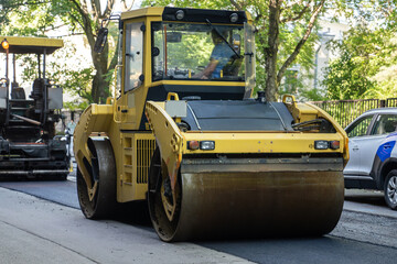 Roller for laying fresh hot asphalt on the road, city street. Road construction equipment. 