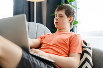 Young man with down syndrome using laptop computer at home