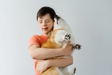Excited teenager with down syndrome holding corgi dog showing love and friendship © Maria Vitkovska