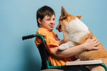 Happy teenager with disability hugging his dog in wheelchair