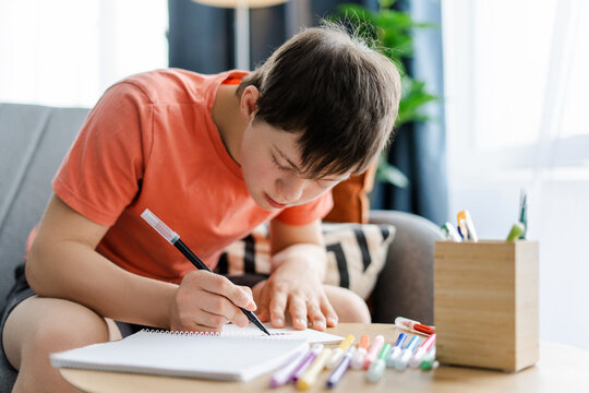 Teen boy with down syndrome drawing with black felt tip pen