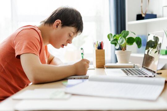 Teenager with down syndrome doing homework concentrating on taking notes