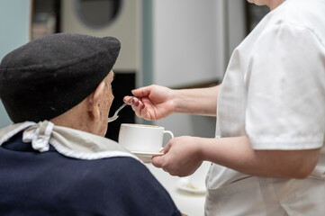 Senior man getting fed by carer in nursing home. High quality photography