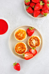 Vegan cheesecakes with strawberries, berries sauce, cashew and tofu. Syrniki, cheese pancakes. Sugar, lactose and gluten free. Vertical orientation, top view.