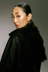 Asian woman, black leather jacket, ponytail hairstyle, looking off to the side fashionable and stylish portrait of a young asian woman