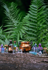 colorful gemstone crystals, witch copper cauldron and magic bottles in forest, natural background....