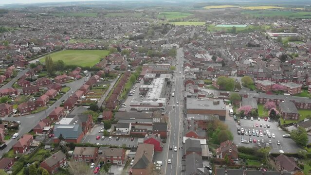 Aerial footage of the Leeds based town of Garforth in West Yorkshire in the UK, showing the main street road on a bad weather dank day