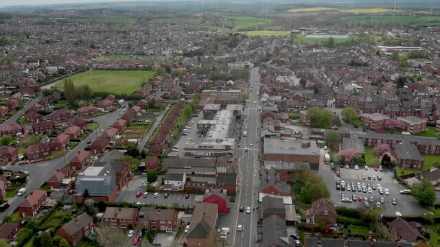 Aerial footage of the Leeds based town of Garforth in West Yorkshire in the UK, showing the main street road on a bad weather dank day showing the drone flying through rain