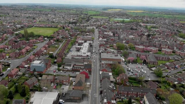 Aerial footage of the Leeds based town of Garforth in West Yorkshire in the UK, showing the main street road on a bad weather dank day showing the drone flying through rain