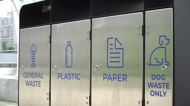 Separate waste containers for general waste, plastic, paper and dog waste in urban environment.