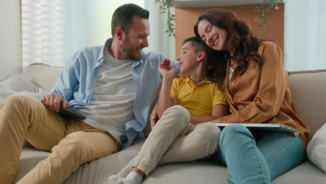 Happy Caucasian family mom dad son parents child kid boy tickling having fun relax on sofa together talking speak cuddle laugh play cuddling loving relationship concept new comfortable home apartment