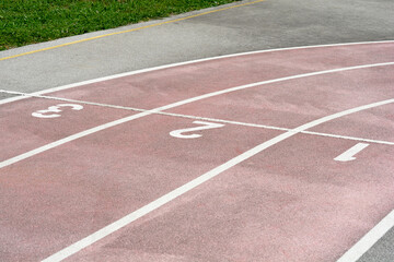 Fototapeta premium Detail of the running track with numbers one, two and three one on a school sports field