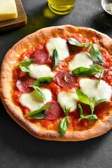 Pizza with mozzarella, pepperoni, tomato sauce and basil