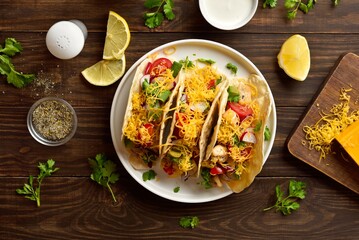 Tacos with vegetables, chicken meat and cheddar cheese over wood