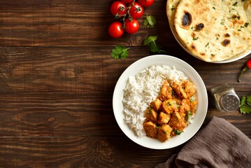 Butter chicken with basmati rice on plate on wooden background