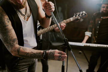 Crop shot of unrecognizable male rock vocalist getting ready for performance adjusting microphone stand