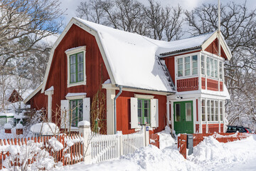 Traditional old big red wooden house in winter countryside. Beautiful Swedish cottage or villa with big windows, glazed terrace and balcony. Christmas landscape in northern Europe. Snowy village.