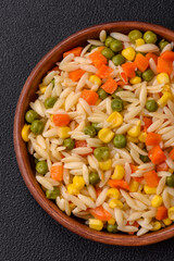 Delicious boiled rice with vegetables corn, carrots, peas with salt