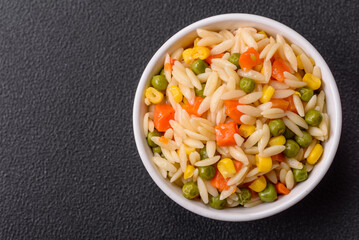 Delicious boiled rice with vegetables corn, carrots, peas with salt