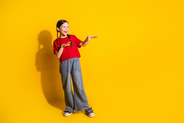 Full size photo of lovely small girl good mood dance empty space wear t-shirt isolated on yellow color background